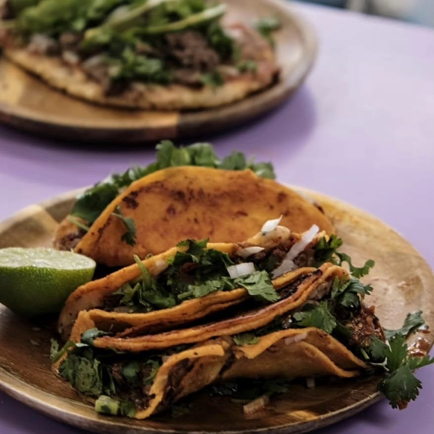 Birria tacos with cilantro and onion on wooden plates at Sison Tacos